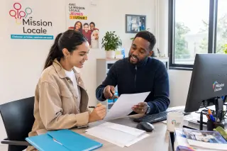 Young woman and advisor collaborating on job application in a bright, welcoming office with natural light and colorful decor, both appearing confident and engaged.