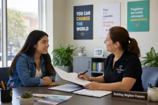 Young adult woman and advisor discussing documents in a bright, modern office, both looking engaged and positive.