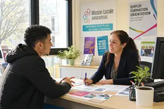 Young man and counselor in a bright, welcoming office, discussing documents together with a positive, collaborative attitude.